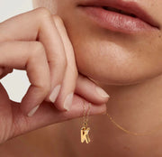 Dainty initial necklace featuring the letter K in gold plating, suspended on an adjustable anchor chain with lobster clasp for everyday elegance.